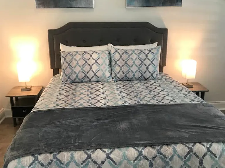 Comfortable queen bed with premium linens, soft pillows, and nightstands with lamps.