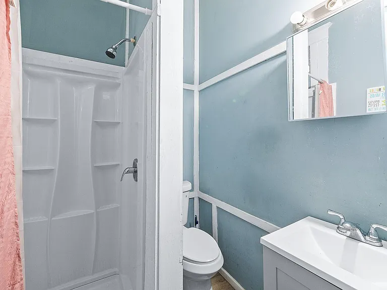 Full bathroom with a walk-in shower, pedestal-style vanity, and mirrored medicine cabinet for everyday storage.
