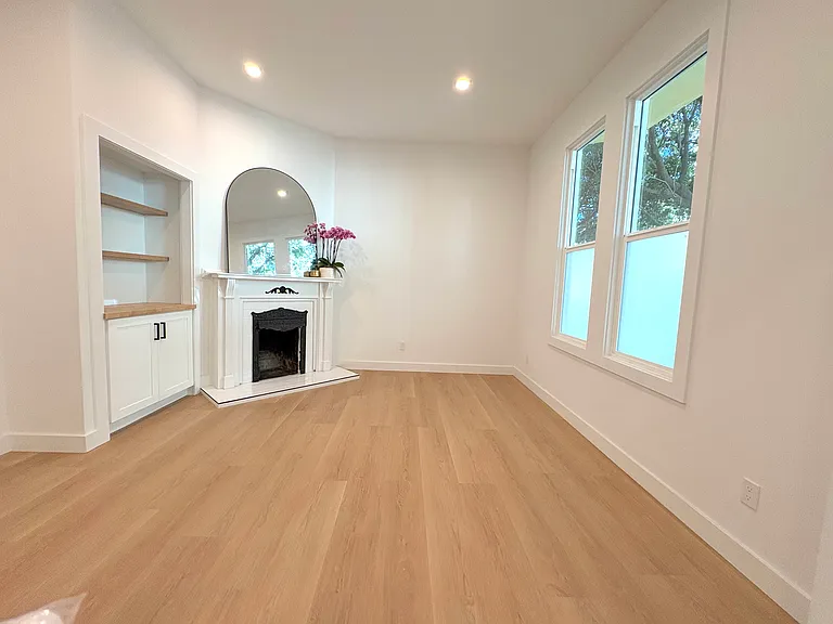 Living room with large windows, decorative fireplace and built in shelving