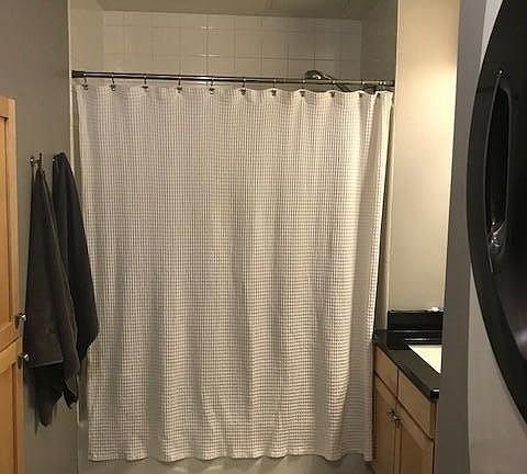 Huge bathroom with full sized front-loading washer and dryer, granite counter vanity, extra built in storage for toiletries, etc. on opposite wall.