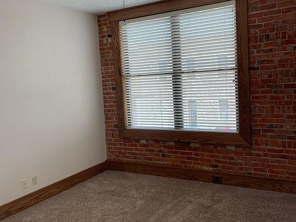Bedroom- exposed brick, ceiling fan, and big windows with blinds
