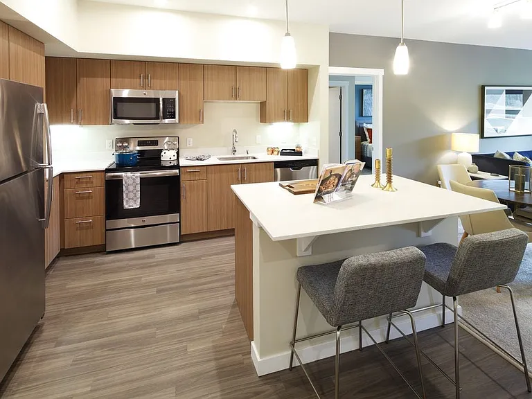 Phase I - Scheme B Kitchen with oak cabinetry, stainless appliances, white quartz countertops, and hard surface flooring
