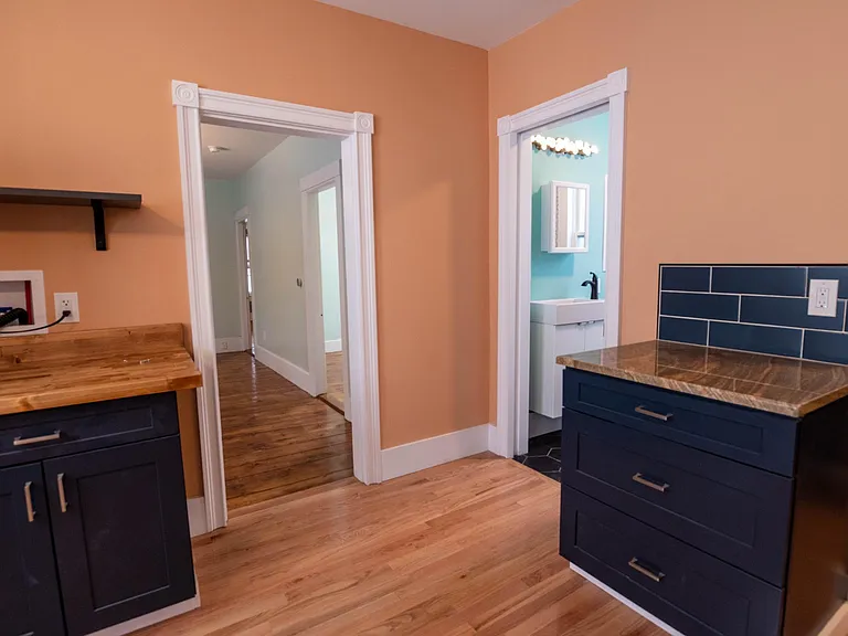 kitchen view showing additional cabinets with granite and butcher block counters, entry to bathroom with pocket door and living room