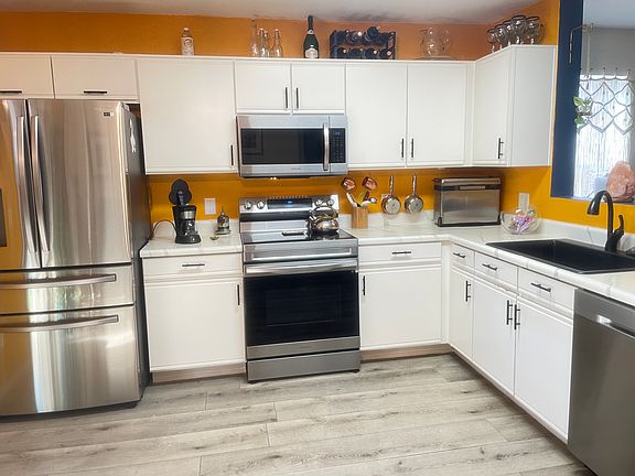 Samsung fridge, microwave, stove, and dishwasher. The light is coming from the sliding back door leading to the covered back patio.