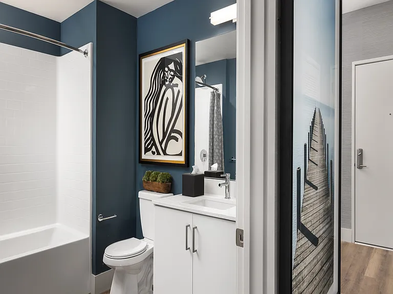 Sophisticated bathroom with modern fixtures, elegant wall art, and a sleek white bathtub offering a perfect blend of style and comfort.