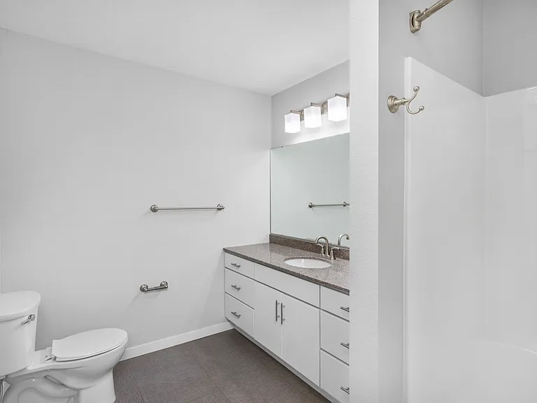 Modern bathroom with sleek white cabinetry, granite countertop, and spacious shower area. Modern bathroom with sleek white cabinetry, granite countertop, and spacious shower area.