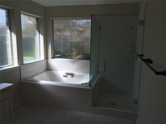 Jacuzzi tub with new tile in shower and tub surround. New seamless glass enclosure. New Rain Glass on all three panels in the back create light with privacy so no need for window coverings.