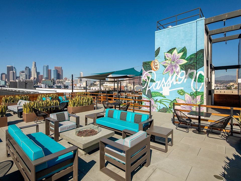 a rooftop patio with blue chairs and tables and a mural on a building