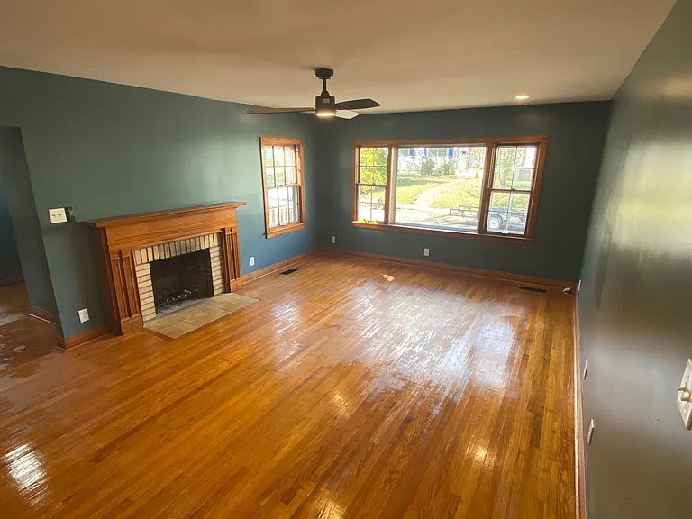 Large open living room with wood burning fireplace and large windows.