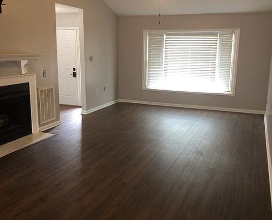Great room with front door to the left, bay window, and fireplace