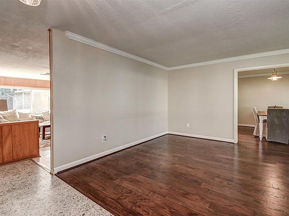 Just inside the door is the very large, lovely formal living room. The hand-scraped engineered wood floors and crown molding were installed in 2012. Formal dining on the right, sunny den on the left.