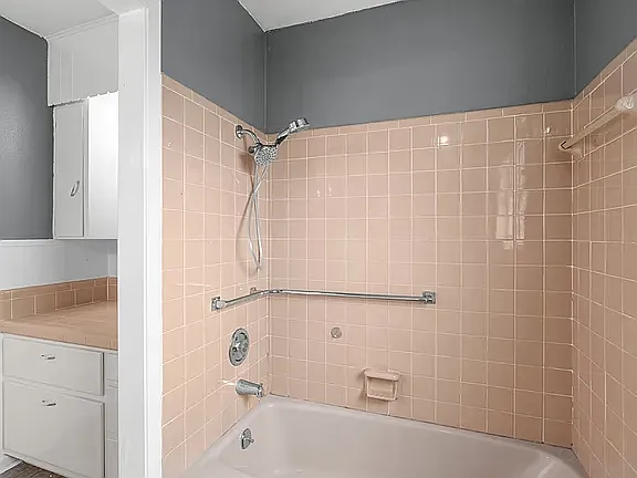 Tub/shower in Hall Bath with grab bars and view of lower cabinets in Dressing Area