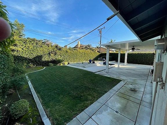 Large backyard with covered patio area, raised seating area and oversized jacuzzi