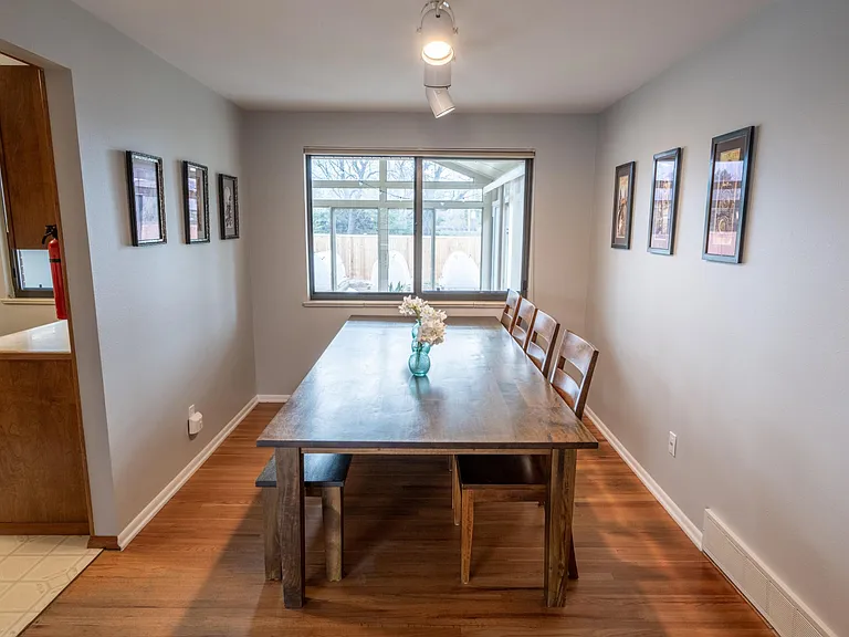 View of the dining room with a large dining table. Through the window you see into the sun room and the back yard. On the left is the entrance to the kitchen.