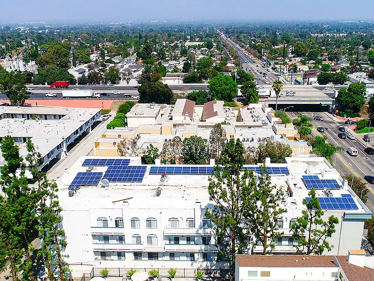 Aerial drone view of Chateau Encino showing energy-efficient white roof, solar panels, and access to 101 freeway.