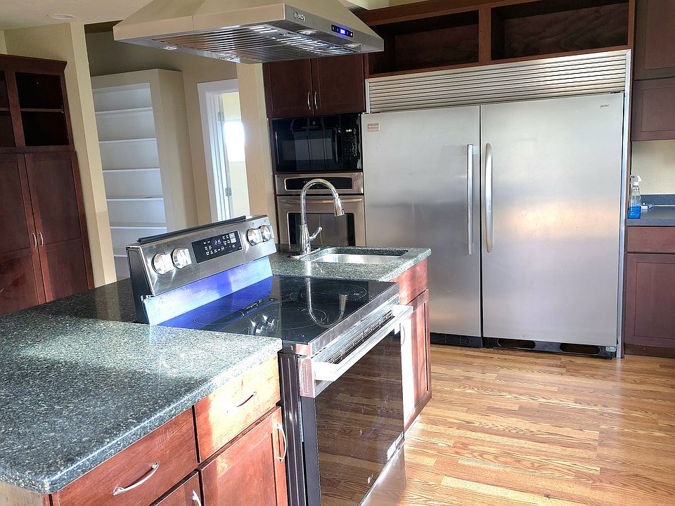 Photo of new stove, exhaust fan, hand washing sink and commercial fridge and freezer.