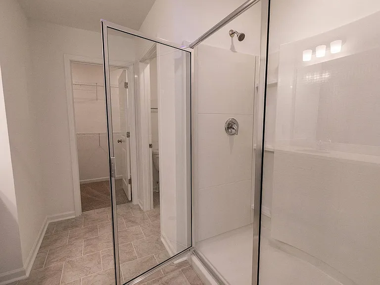 Refined primary bathroom complete with a double vanity, walk-in shower, and walk-in closet.