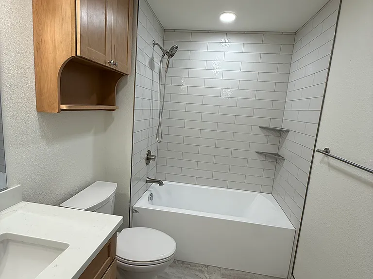 Lower full bath has a tub with tiled surround and flooring.