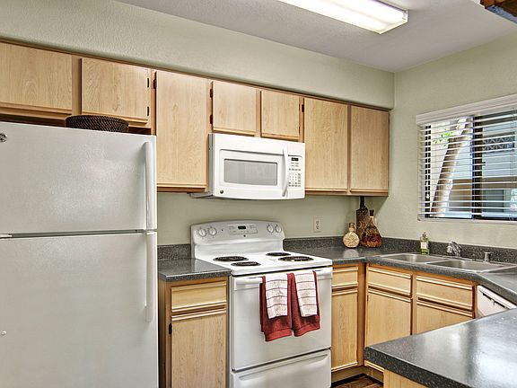 A kitchen with light cabinets and white appliances