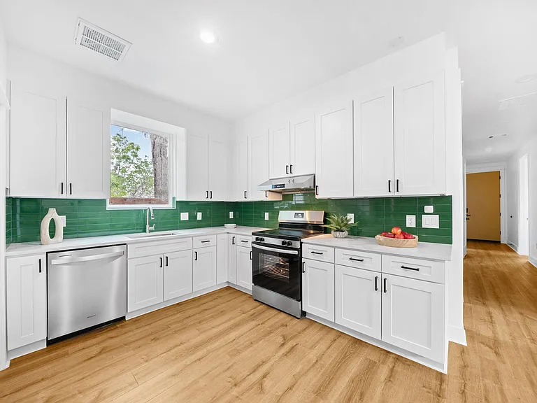 Updated L-shaped kitchen with shaker cabinets, stainless appliances, and ample counter space plus a window over the sink.