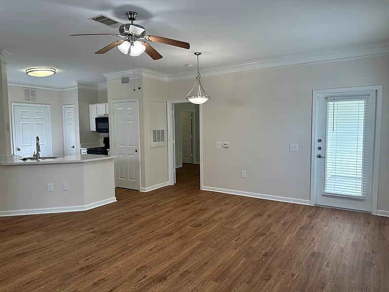 Bright and airy open-concept living area with modern kitchen, stylish ceiling fan, and elegant wood-style flooring. Bright and airy open-concept living area with modern kitchen, stylish ceiling fan, and elegant wood-style flooring.