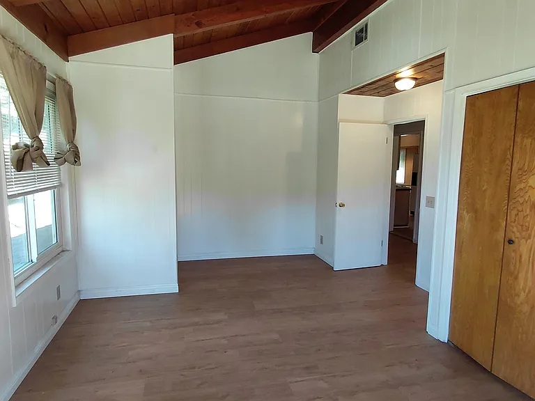 Oversized bedroom with vaulted wood-beam ceilings.