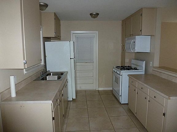 Kitchen recently updated with neutral color laminated counters, stove, microwave and refrigerator