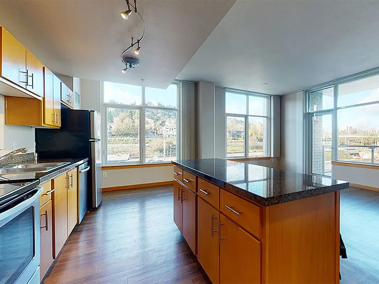 Apartment Kitchen with Stainless Steel Appliances, Dining and Living Room with Wood-Style Flooring.