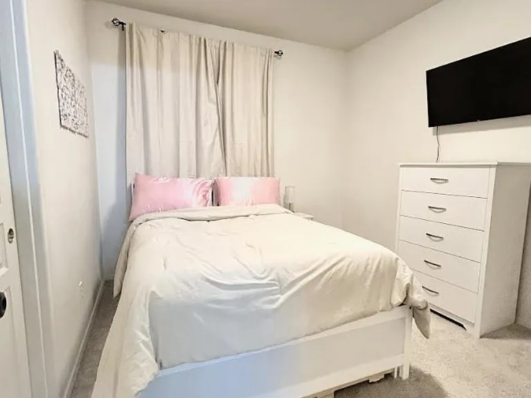 3rd bedroom with plush full-size bed, a pull-out trundle twin bed, closet, tall dresser, mounted smart tv, black out curtains.
