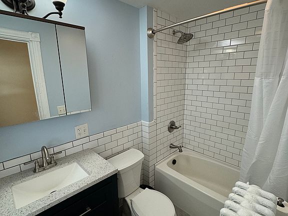 Renovated bathroom with non-slip tile floor, new vanity and shower fixtures, fresh tile, and new paint and N&S Supply fixtures.