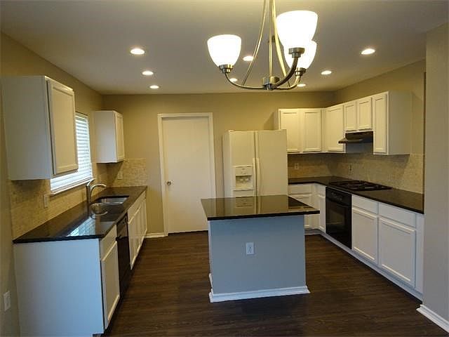 beautiful kitchen remodel with granite counter tops, a travertine backsplash, a breakfast bar on the kitchen island, LED recessed lighting, and new light fixtures.  The kitchen is open to the dining room and living room.