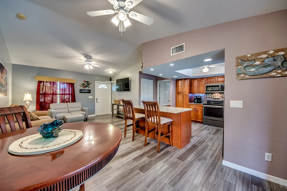 Photo 1 of 10 - SE 27th St - Cape Coral, FL Dining, kitchen, and living areas. Door to laundry is to the right of the TV. Laundry also opens to garage. - SE 27th St