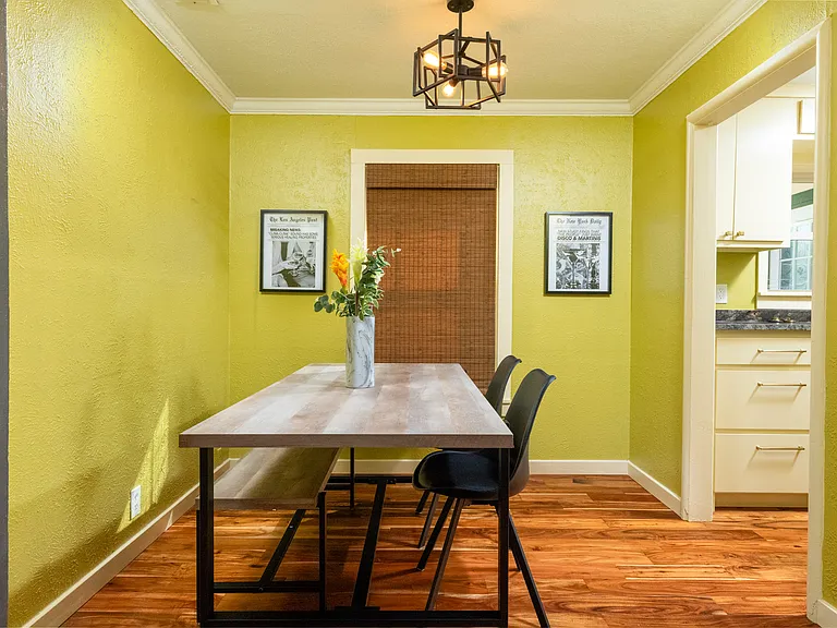 Cozy dining nook with a modern farmhouse table, soft lighting, and warm green walls. Perfect for enjoying meals, morning coffee, or working in a relaxed atmosphere.