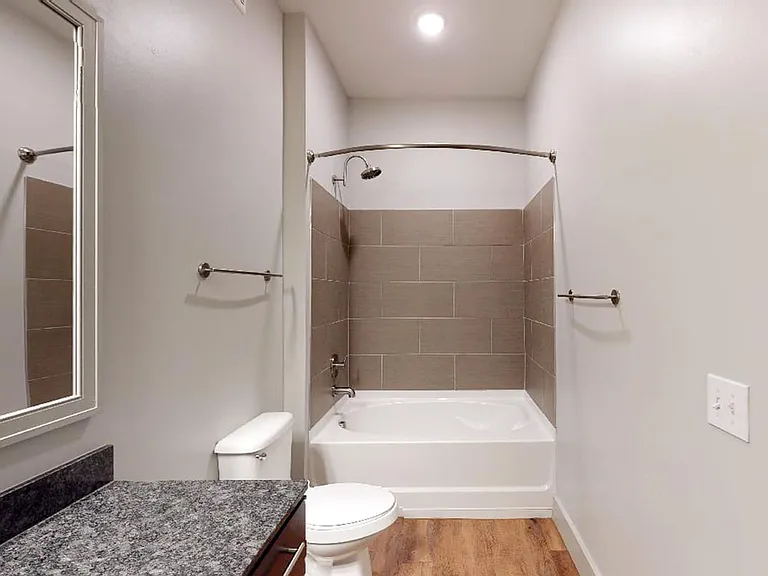 Apartment bathroom with large soaking tub and wood-style flooring.
