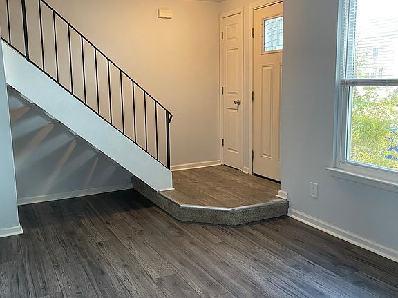 View from kitchen of front door closed, with coat closet at bottom of stairs
