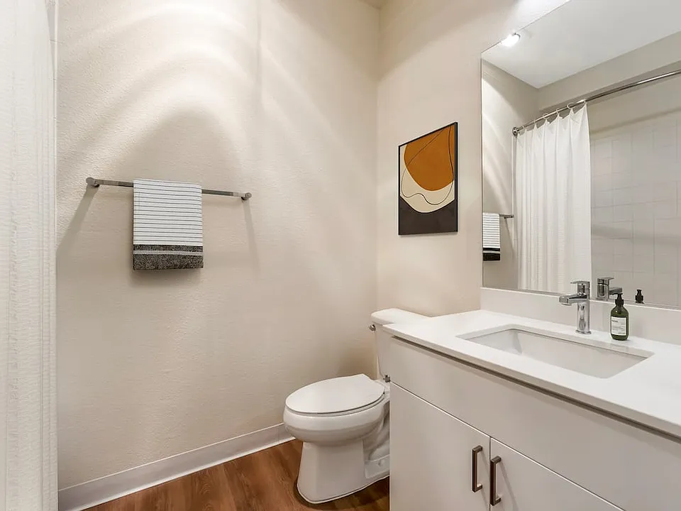 Renovated Package I bath with white quartz countertop, white cabinetry, and hard surface flooring