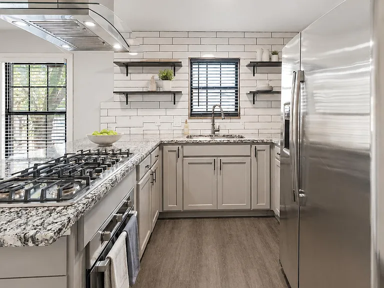 Updated kitchen with granite counters, stainless appliances, gas cooktop, and open shelving for everyday storage.