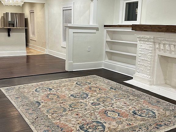 Looking inside the front door. Living room offers ceiling fan, can lights in ceiling along w/a faux fireplace with mantle and loads of shelves!