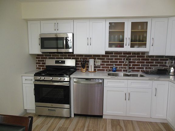 Kitchen showing gas stove, dishwasher, quartz countertop and built in microwave oven.