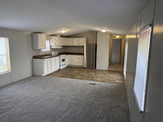 Open kitchen with modern fridge and white stove.