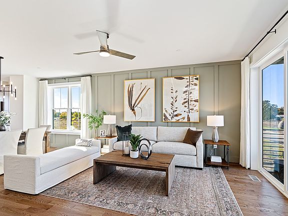 Modern living room with neutral tones, large windows, wall art, and a wooden coffee table with plant