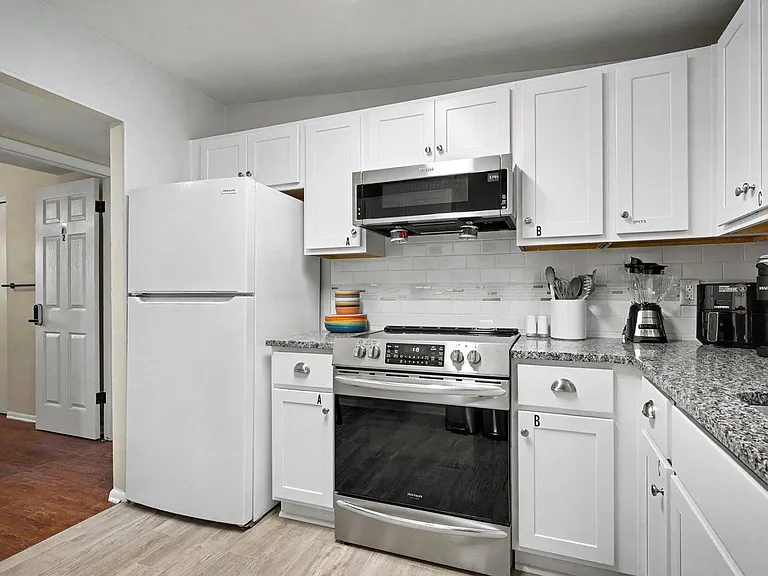 Updated kitchen with shaker cabinets, granite countertops, tile backsplash, and countertop small appliances