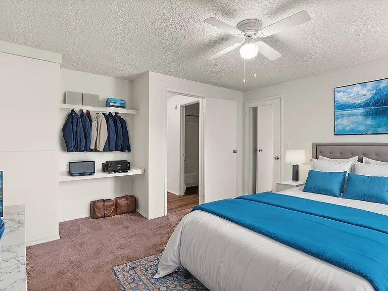 Relax in a spacious bedroom featuring soft carpet, a ceiling fan, and convenient built-in storage.