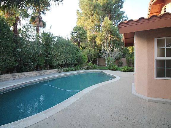 Pool is surrounded by a variety of flowering trees, bushes and palms