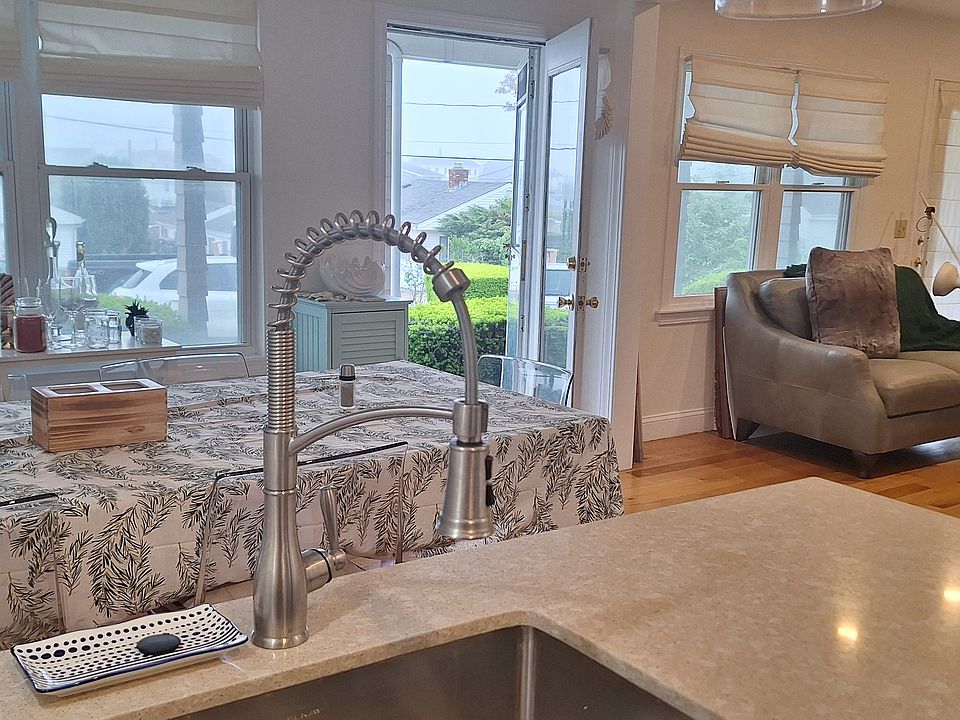 One of 2 doors entering from front deck into open space living-room seen on the right, dining-area, and kitchen. Through the windows parking and facing west and sunsets.