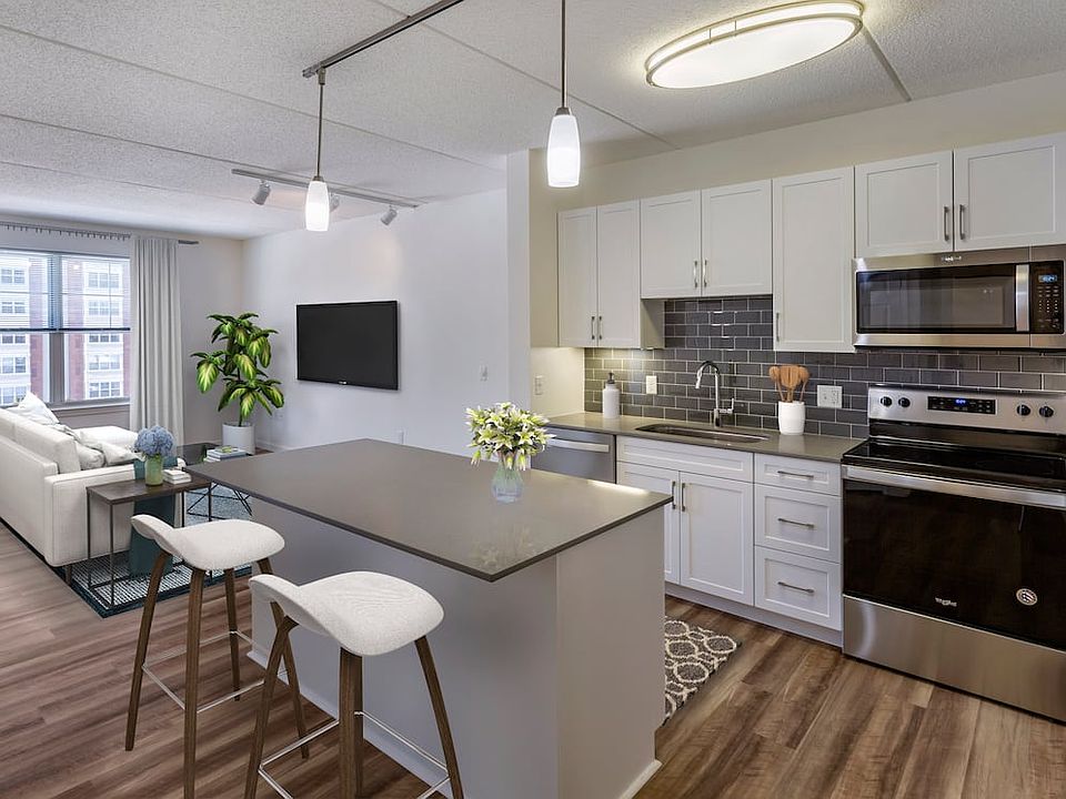 Renovated Package II kitchen with grey quartz countertops, white shaker cabinetry, stainless steel appliances, grey tile backsplash, and hard surface flooring throughout
