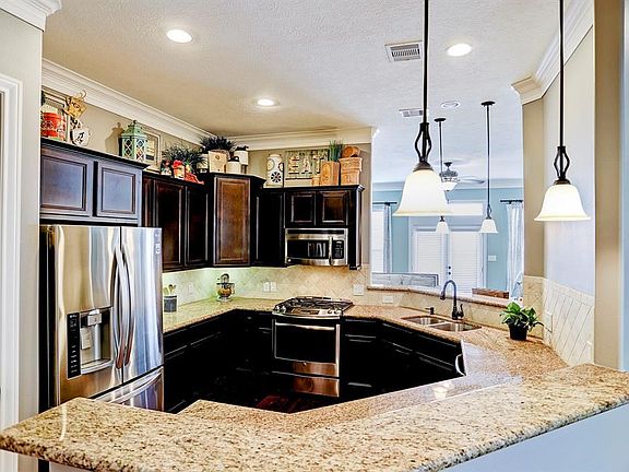 The kitchen showcases granite countertops, SS appliances, including a wine fridge and rich dark wood cabinets. This gives the kitchen such a sleek look.