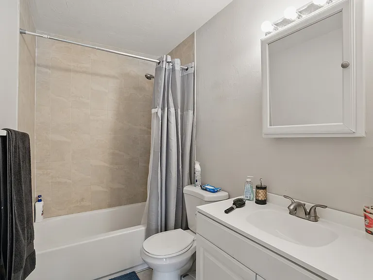 The bathroom is clean and modern, featuring a fully tiled shower, updated fixtures, and a bright, functional layout designed for everyday comfort