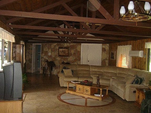 ranch style living room with stone walls and wood beams