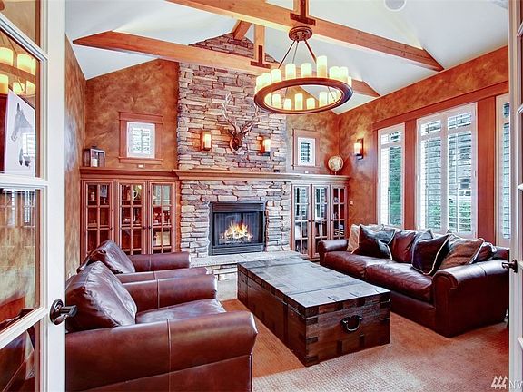Stunning office or study off the foyer features a vaulted timber beamed ceiling, floor to ceiling stacked stone gas fireplace with raised hearth flanked with built-in bookshelves, sconce lighting and candelabra chandelier; the perfect spot to have conversations with friends or get some important work done. 